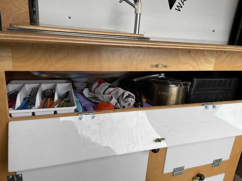  clean stainless steel sink with a white faucet on a dark wood counter.|RV rental: A compact van kitchenette with a sink — photo 5