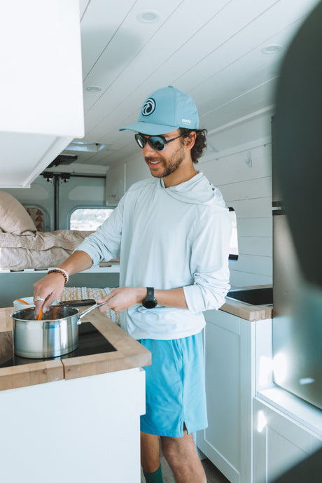 Man cooking a meal in a bright, modern RV rental kitchen, perfect for van life adventures on the road!