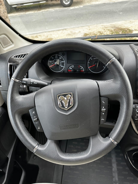 Inside an rv rental: Ram steering wheel with controls & dashboard gauges visible for the driver.