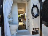 Inside a modern RV rental, featuring a shower, toilet, storage cabinets, and electrical hookups. Ready for adventure!