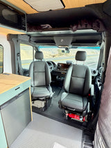 RV rental campervan interior: front cabin with dual seats, microwave, fridge, and overhead storage for comfortable travel.