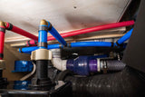 RV rental: PEX water lines (red for hot, blue for cold) and drainage pipes visible within the vehicle's utility space.