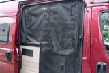 An RV rental's red van with an open side door, protected by a black screen, showing its camper van conversion.