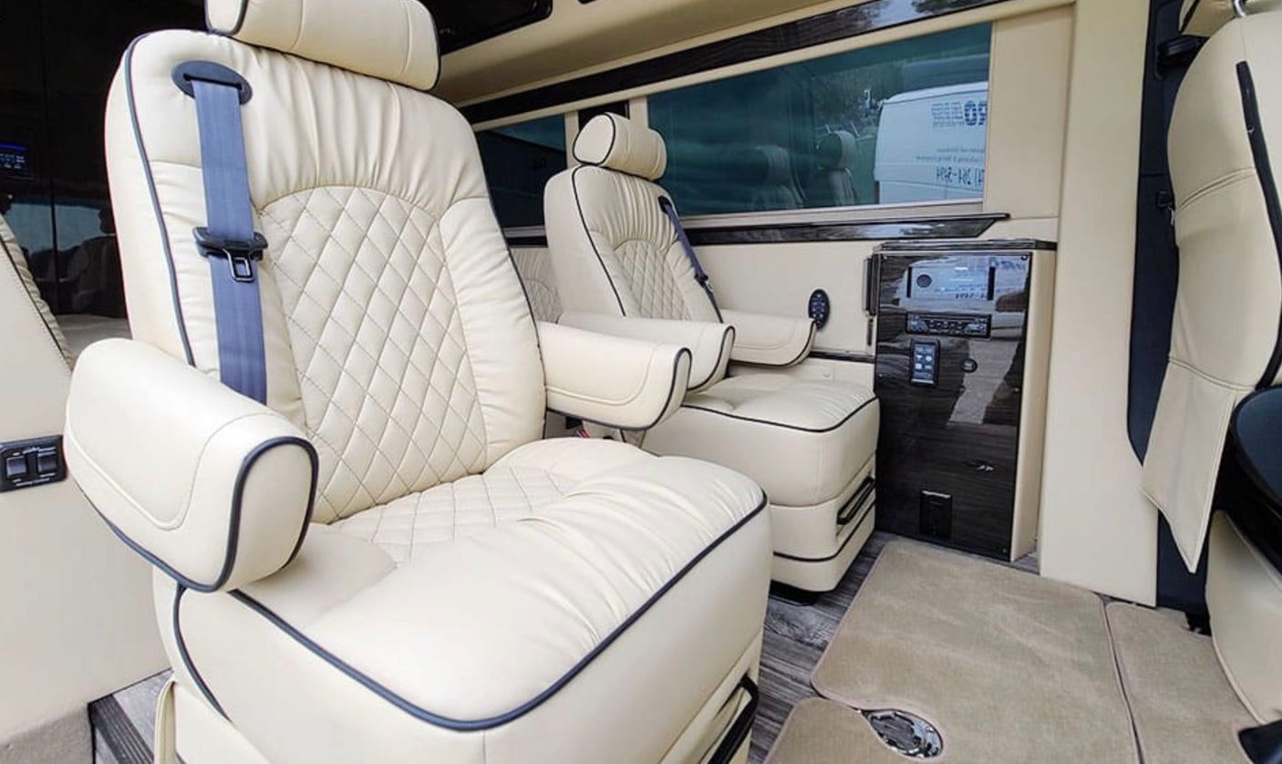 Plush RV rental interior featuring cream leather captain seats with diamond quilting and integrated controls for comfort.