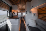 RV rental interior: Modern camper van with a cozy living area, kitchenette, and panoramic beach views.