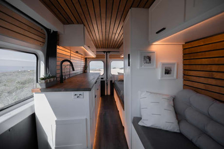 RV rental interior: Modern camper van with a cozy living area, kitchenette, and panoramic beach views.