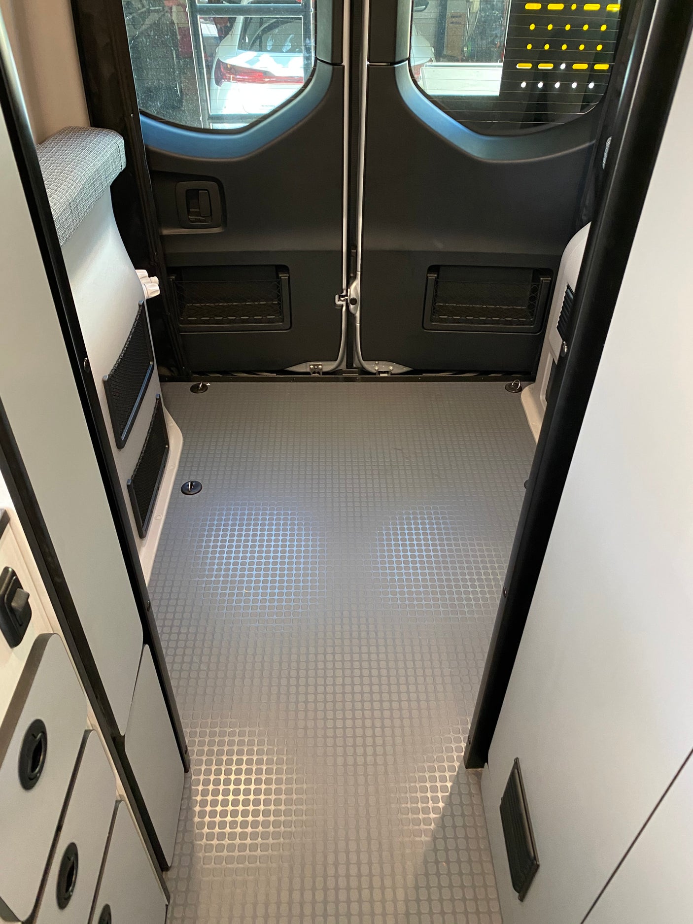 Looking into the rear of an RV rental: clean cargo area, textured floor, and side storage. Ideal compact camper van space.