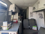 This RV rental's interior features a well-equipped kitchenette, comfortable seating, overhead storage, and nature decals.