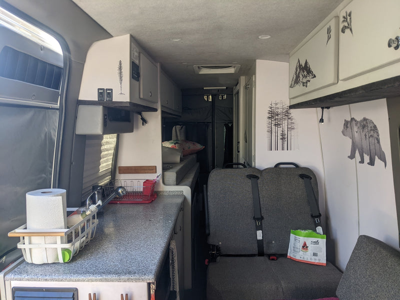  parked on a dirt path next to a reflective puddle.|A silver Mercedes-Benz Sprinter camper van — photo 10