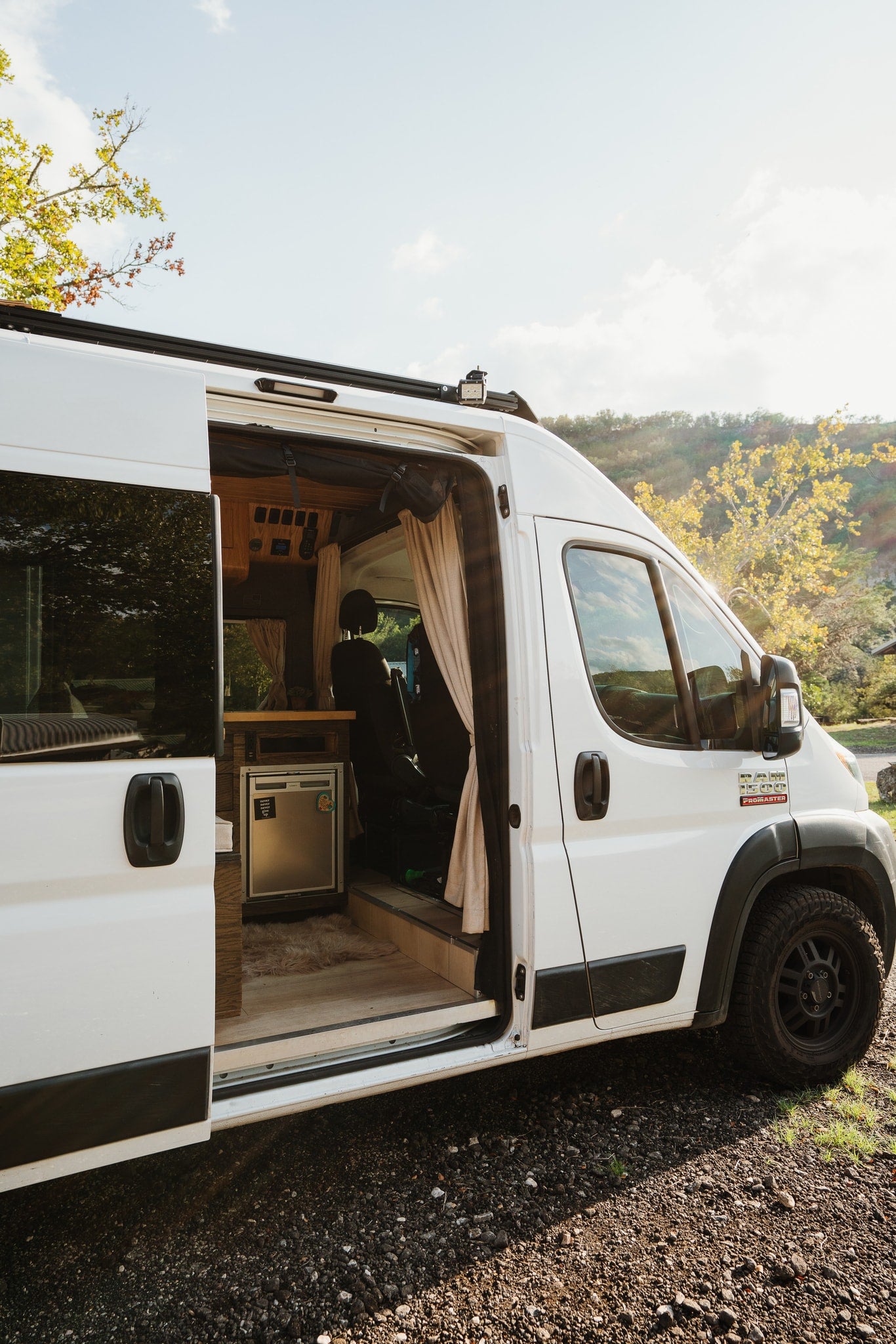 White **rv rental** camper van, side door open to its custom interior with a fridge and cozy details for travel. — photo 11