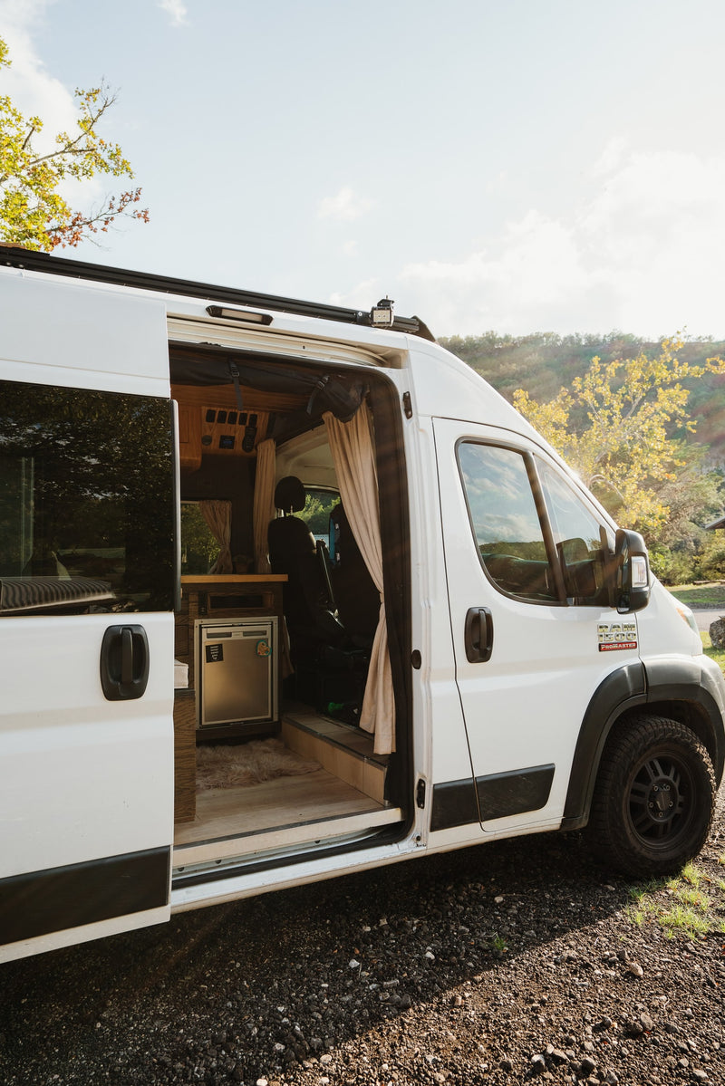 White **rv rental** camper van, side door open to its custom interior with a fridge and cozy details for travel. — photo 11