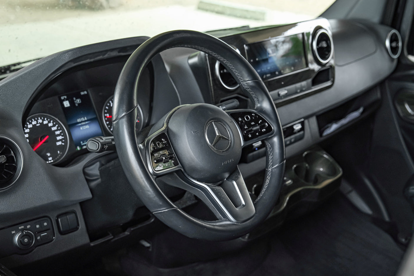 Driver's perspective inside a modern RV rental, showing the Mercedes-Benz dashboard, steering wheel, and instrument cluster.