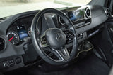 Driver's perspective inside a modern RV rental, showing the Mercedes-Benz dashboard, steering wheel, and instrument cluster.