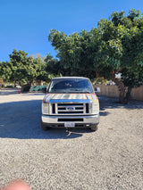Sunny day view of a white Ford van, perfect for your next rv rental adventure. Parked on a gravel lot.
