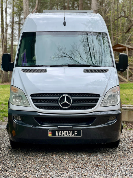 Front view of a white Mercedes Sprinter van with a custom "VANDALF" plate. Ideal for an RV rental, travel, or campervan adventure.