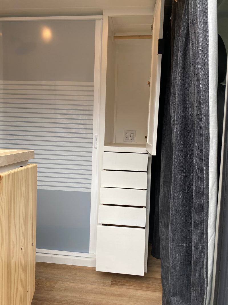 RV rental: Bright interior with a white wardrobe, five drawers, power outlets, and a frosted sliding door. — photo 9