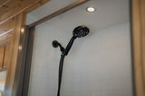 Step into comfort: This RV rental bathroom features a modern black shower head, white tiled walls, and a bright ceiling light.