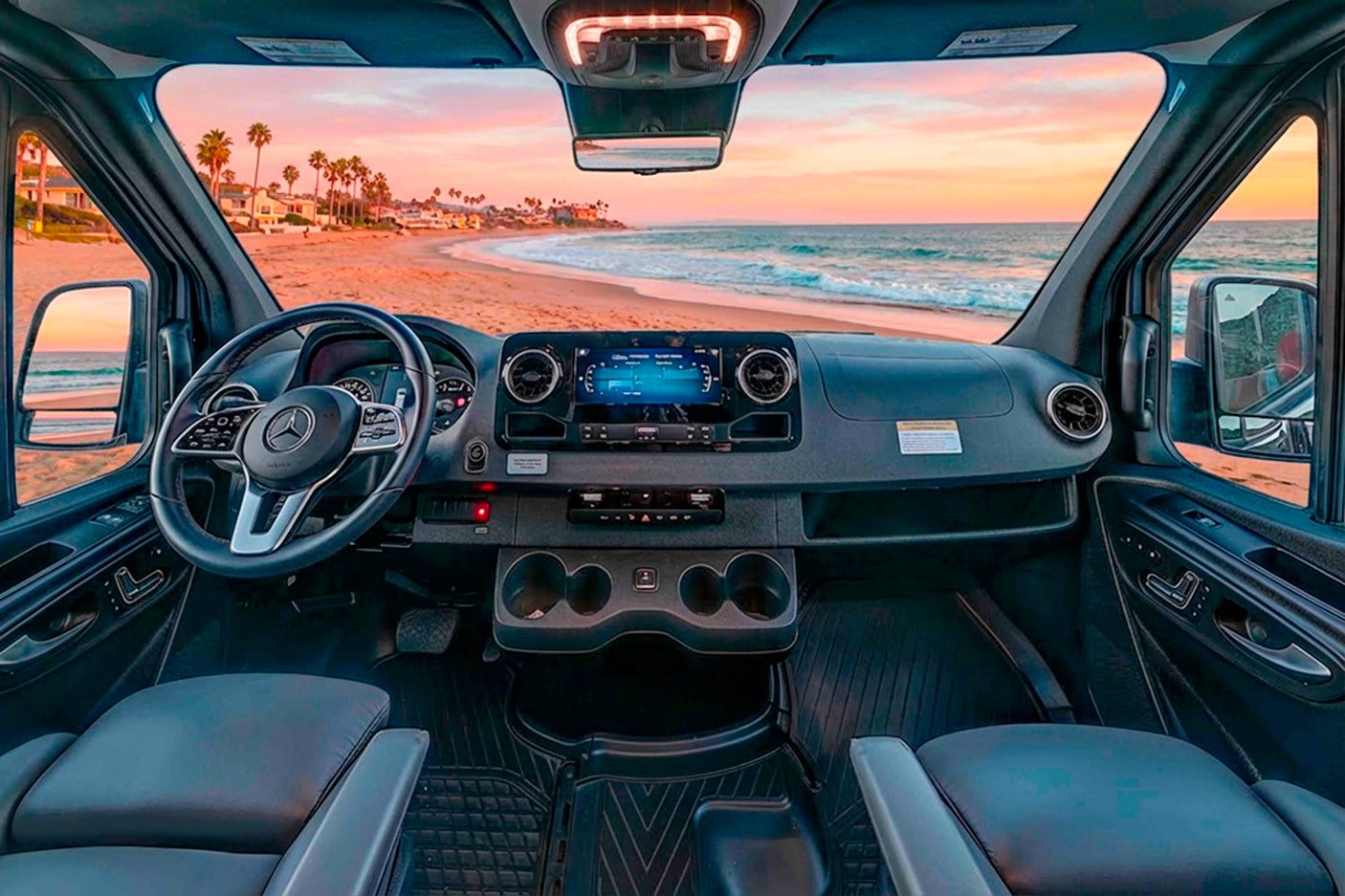 Enjoy a scenic beach sunset from an RV rental, showing the spacious cabin with a modern dashboard, steering wheel, and comfortable seats.
