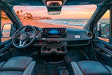 Enjoy a scenic beach sunset from an RV rental, showing the spacious cabin with a modern dashboard, steering wheel, and comfortable seats.
