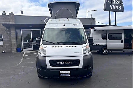 White Ram ProMaster camper van for RV rental, parked at Classic Vans dealership.