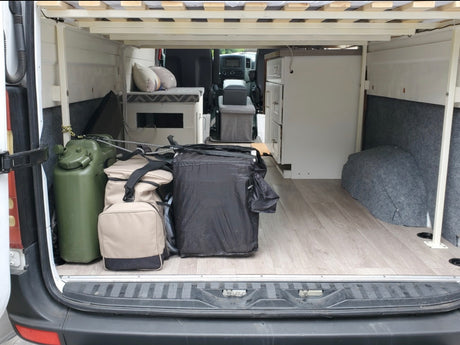 RV rental: Camper van interior features elevated bed, under-bed storage, a water can, and built-in cabinet.