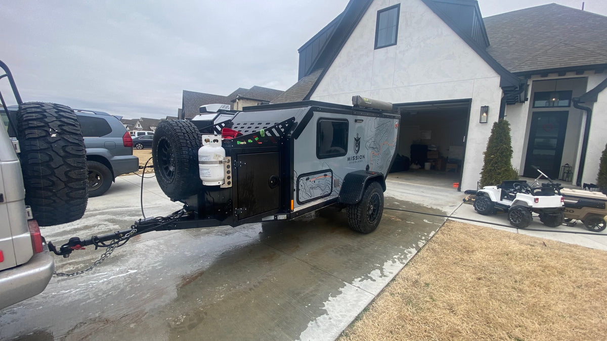  and truck. Consider this RV rental for adventure.|Overland RV rental adventure: Gray SUV towing a trailer on a dirt road through scenic mountain forests.|A G-Wagon tows a sleek Mission Overland RV trailer — photo 15