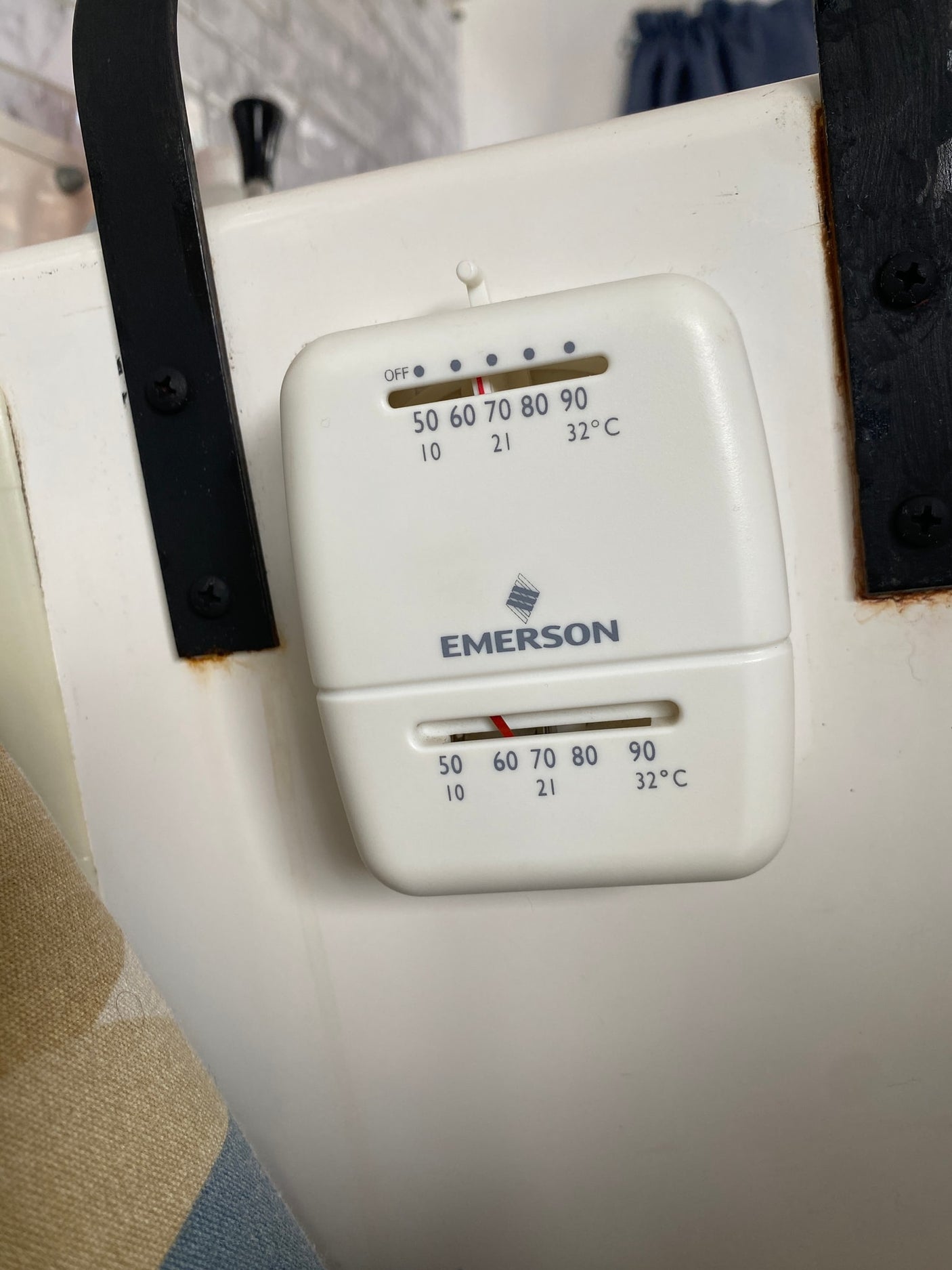 Emerson thermostat in an RV rental. Dual sliders adjust climate control, showing Fahrenheit/Celsius settings on the white unit.