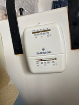Emerson thermostat in an RV rental. Dual sliders adjust climate control, showing Fahrenheit/Celsius settings on the white unit.
