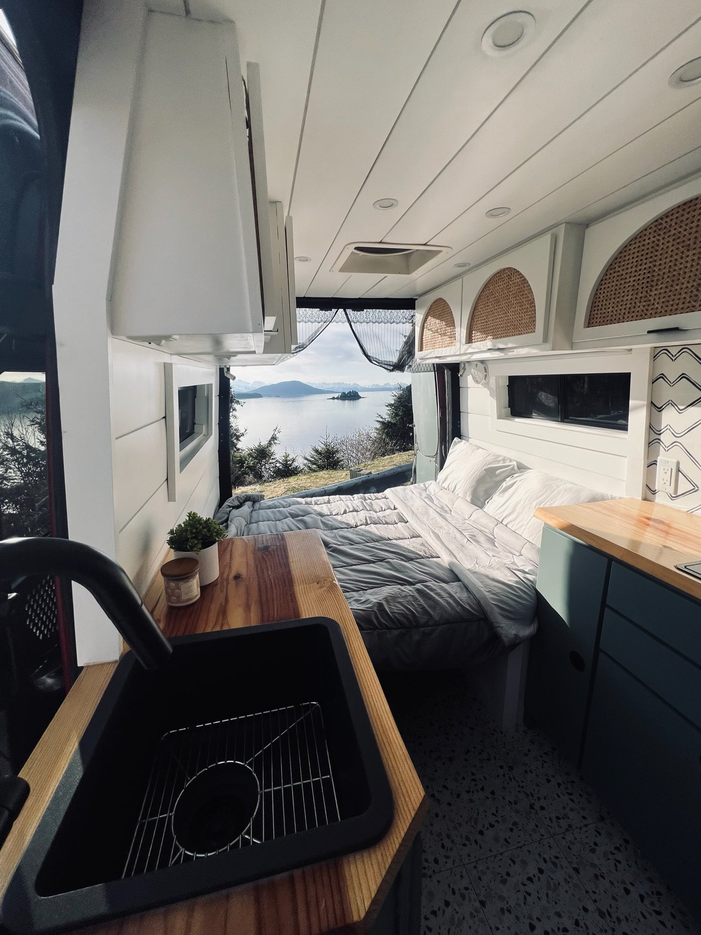 Stunning rv rental interior: comfortable bed & kitchen with a vast, scenic lake and mountain view.