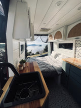 Stunning rv rental interior: comfortable bed & kitchen with a vast, scenic lake and mountain view.