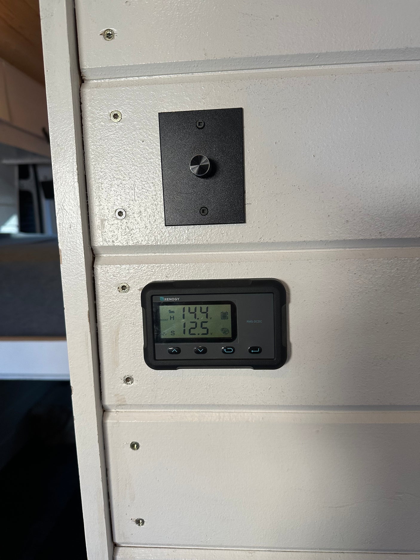 Renogy battery monitor and control panel inside an RV rental, showing 14.4V and 12.5V.