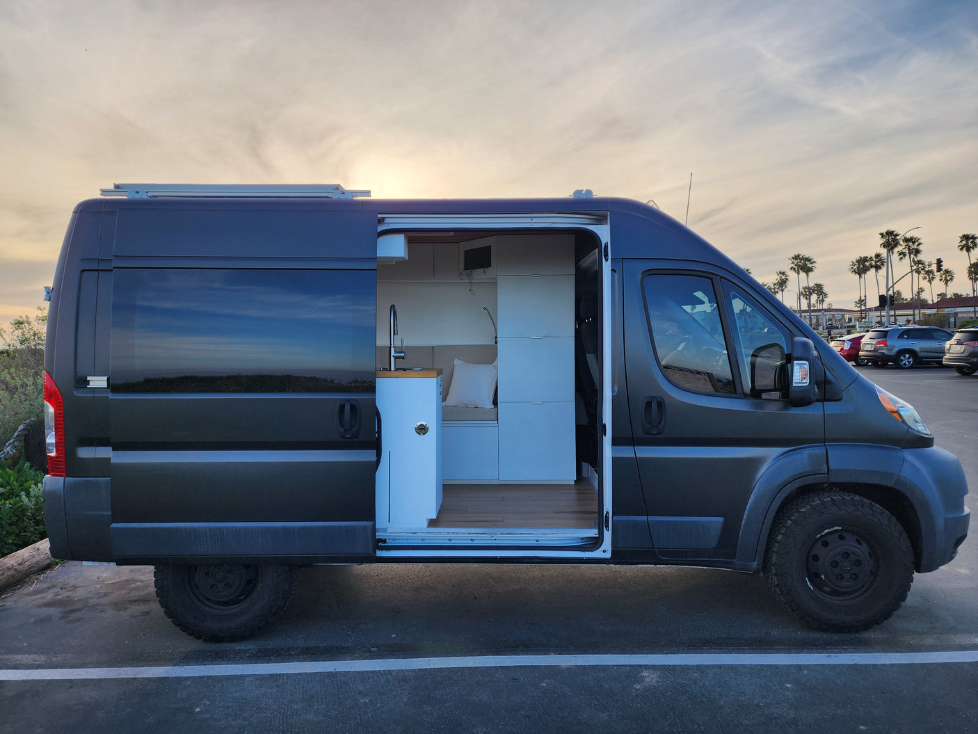 Modern dark grey camper van with open door revealing a stylish, functional interior. Perfect for your next rv rental trip!