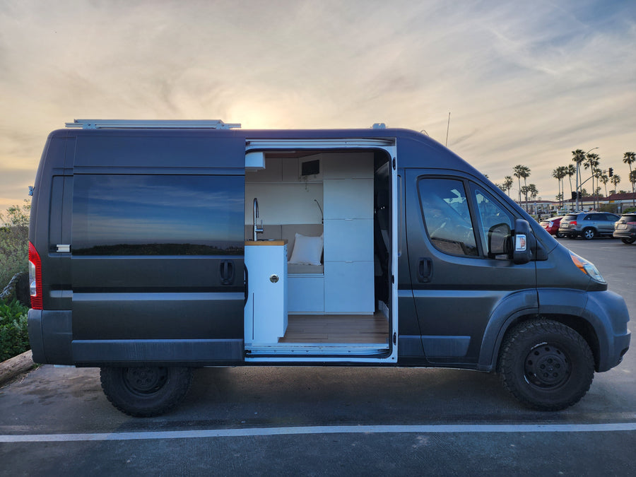 Modern dark grey camper van with open door revealing a stylish, functional interior. Perfect for your next rv rental trip!