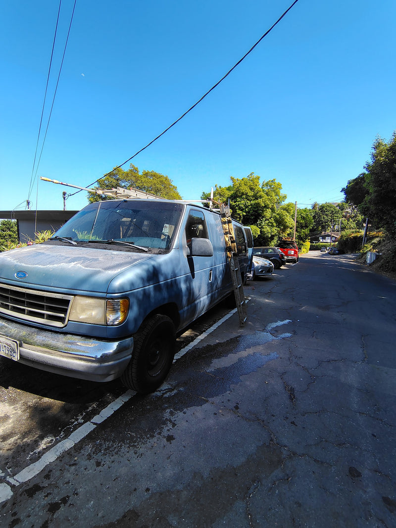 Blue Ford van with a ladder, on a sunlit street. This model is often used for RV rental conversions. A crescent moon is visible. — photo 6