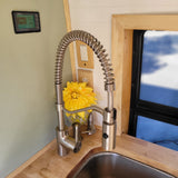 A stylish RV rental kitchen with a large pull-down spring faucet, wood countertop, and a digital battery monitor screen.