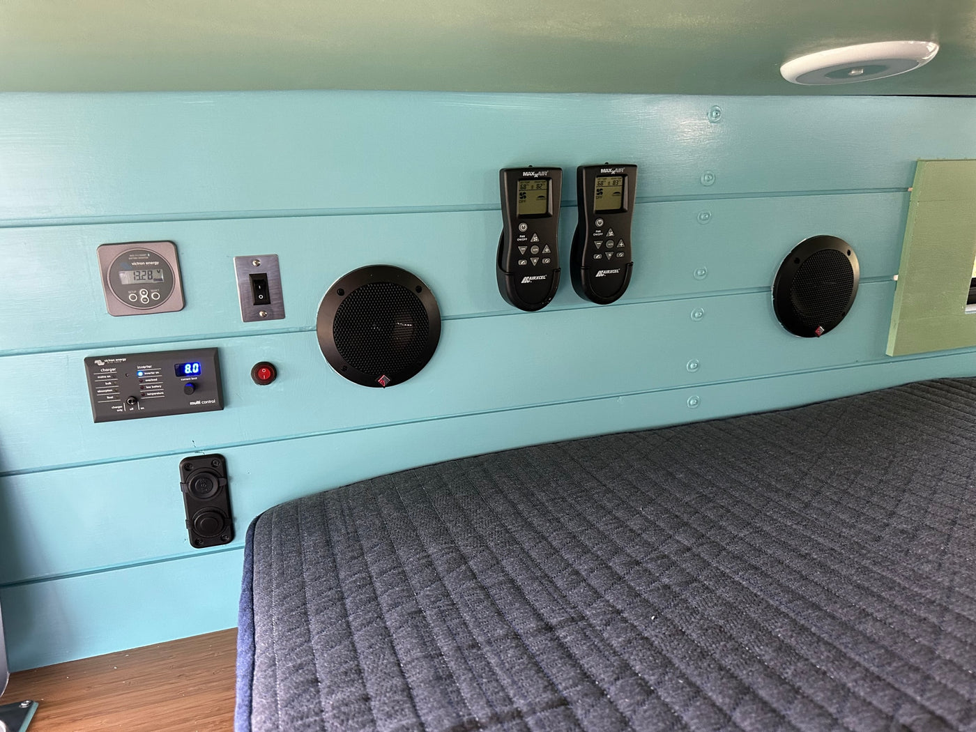 RV rental interior: Victron Energy power, Maxx Air climate, and audio controls on a blue wall above a bed. Optimized for comfort. — photo 11