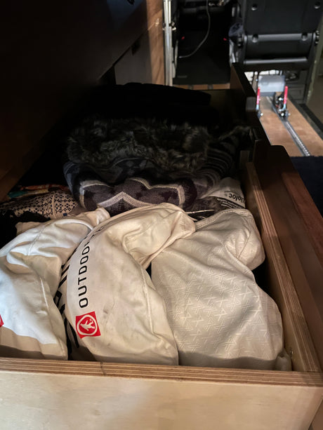 RV rental: A wooden drawer stores neatly folded outdoor gear and clothing, ready for travel.