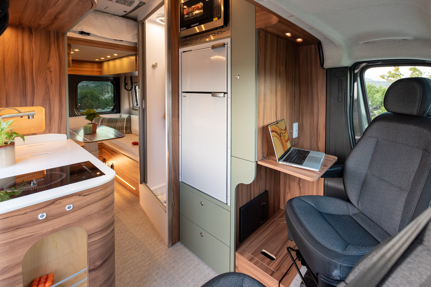 Modern rv rental interior with a kitchen, refrigerator, microwave, laptop workstation, and dining area. — photo 13