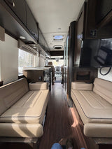 RV rental interior showcasing a comfortable, spacious living area with facing benches, wood floor, and storage.