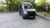 This black Mercedes Sprinter van is a great RV rental option, parked with its side door open near a trail sign.