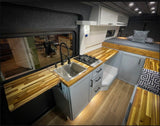 Modern RV rental: a stylish van conversion with a full kitchen, wood counters, comfortable bed, and smart storage.