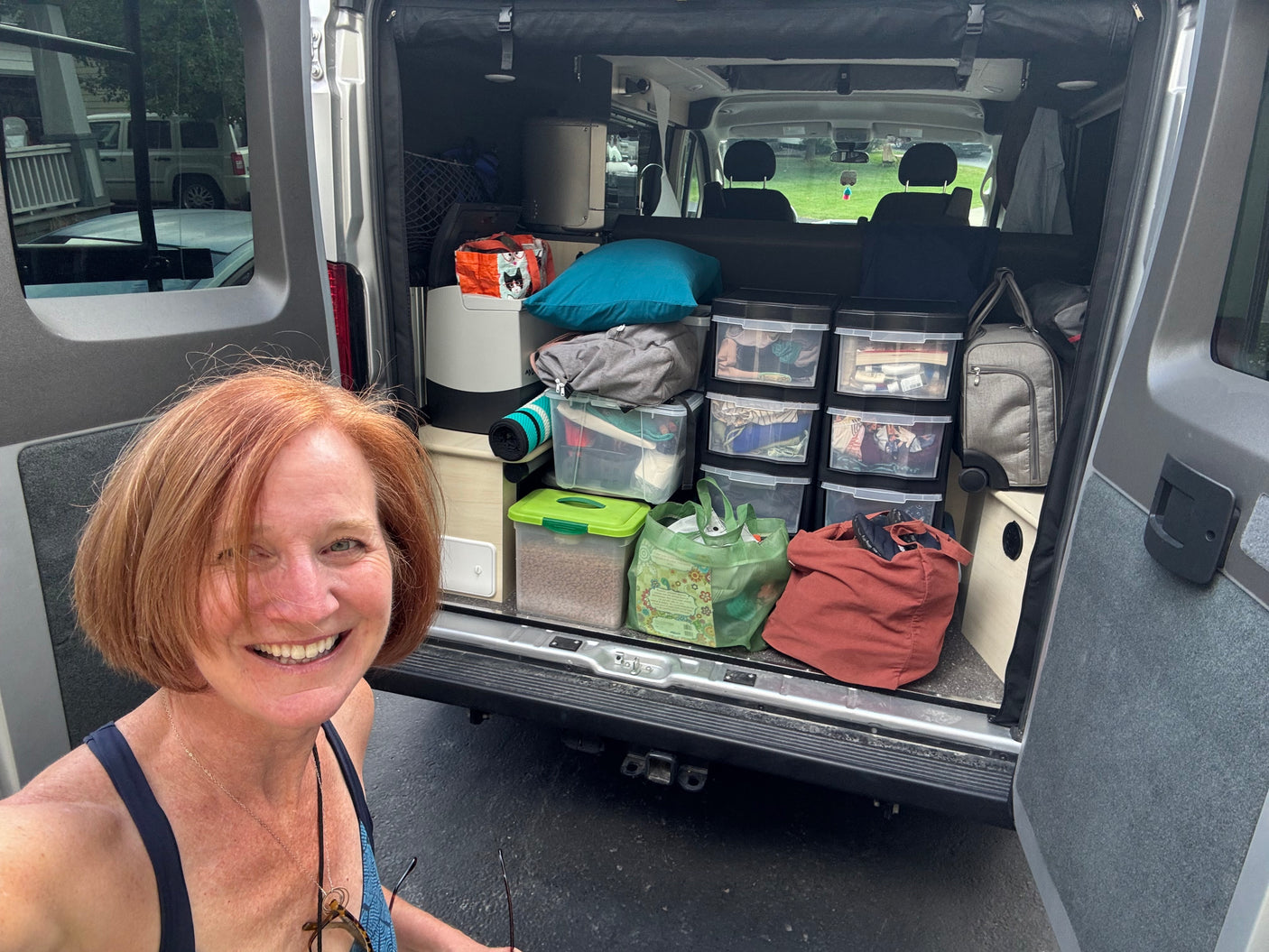 Smiling woman shows off her organized, packed RV rental camper van, ready for an adventure.