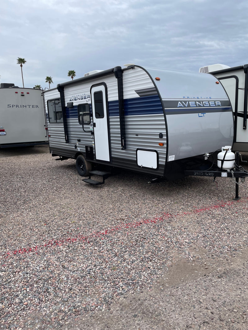 A modern gray and blue 'Avenger LT' travel trailer, perfect for RV rental adventures, parked on a gravel lot. — photo 2