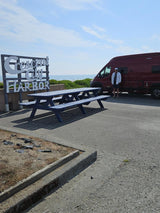 Coastal RV rental at Crescent City Harbor. A man stands by his red van, ocean views, and blue picnic table.