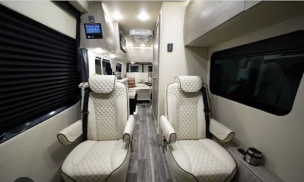 Explore this stylish RV rental interior, featuring plush, quilted seats, and a modern layout leading to the living area.