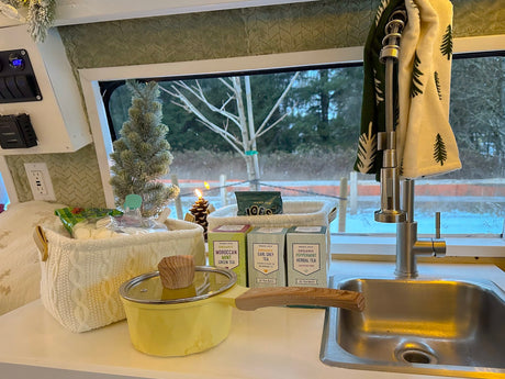 Cozy RV rental kitchen with Trader Joe's teas, a pot, and a festive tree, overlooking a snowy landscape.