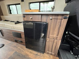 This rv rental features a compact kitchen with a built-in fridge, sink, and comfortable bench seating inside.
