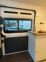 RV rental interior: practical kitchen with sink, overhead storage, and side window street view.