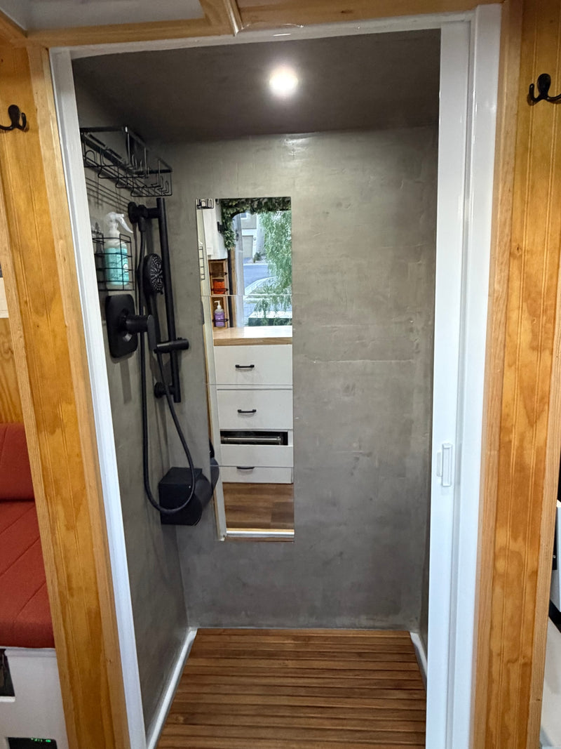Modern RV rental shower with sleek black fixtures, grey walls, and a wooden slatted floor. Compact and refreshing. — photo 18