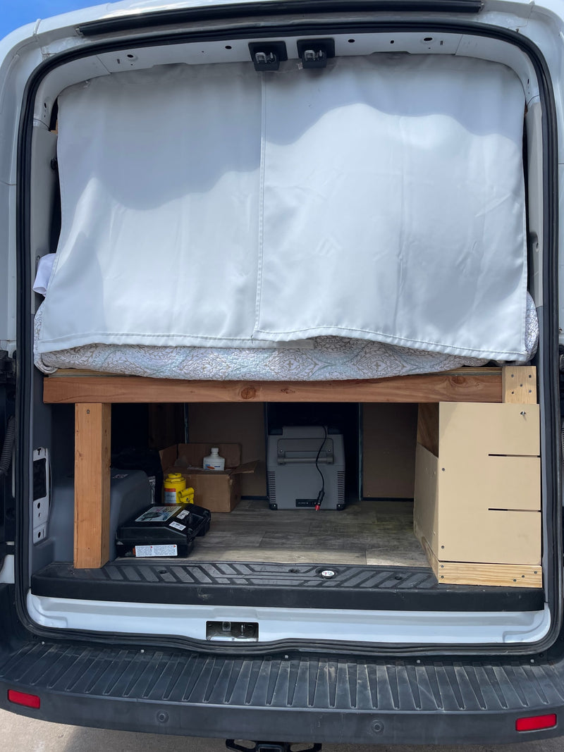 Inside an RV rental van: custom bed with privacy curtain, under-bed storage featuring a portable cooler. — photo 8